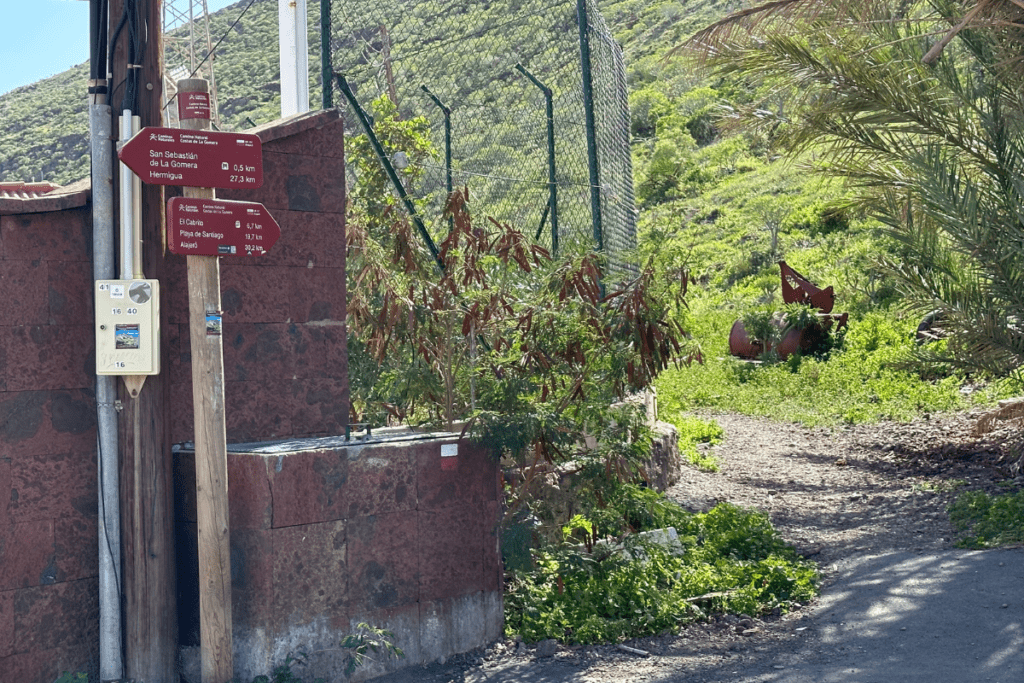 Inicio del sendero para caminar muestra el cartel y la valla metálica con camino al lado Senderismo a la Playa de La Guancha desde San Sebastián Islas Canarias