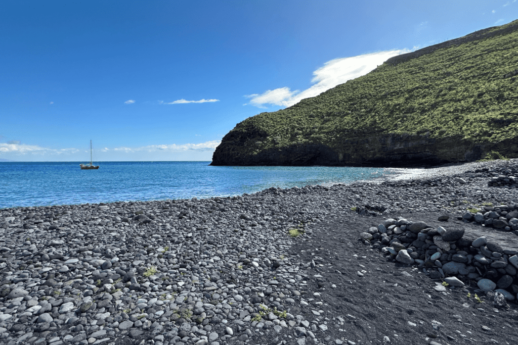 Playa De Avalos, auch bekannt als Avalos-Strand, La Gomera, Kanarische Inseln, Spanien, kieseliger Vulkanstrand mit blauem Meer, blauem Himmel und dramatischen Klippen mit Blick nach Südosten