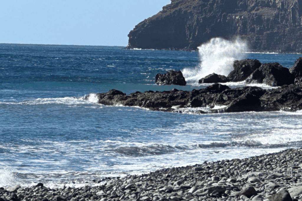 Playa de La Guancha La Gomera, cerca de San Sebastián, también conocida como Playa Guancha Islas Canarias España Olas rompiendo en rocas negras bajo el cielo azul