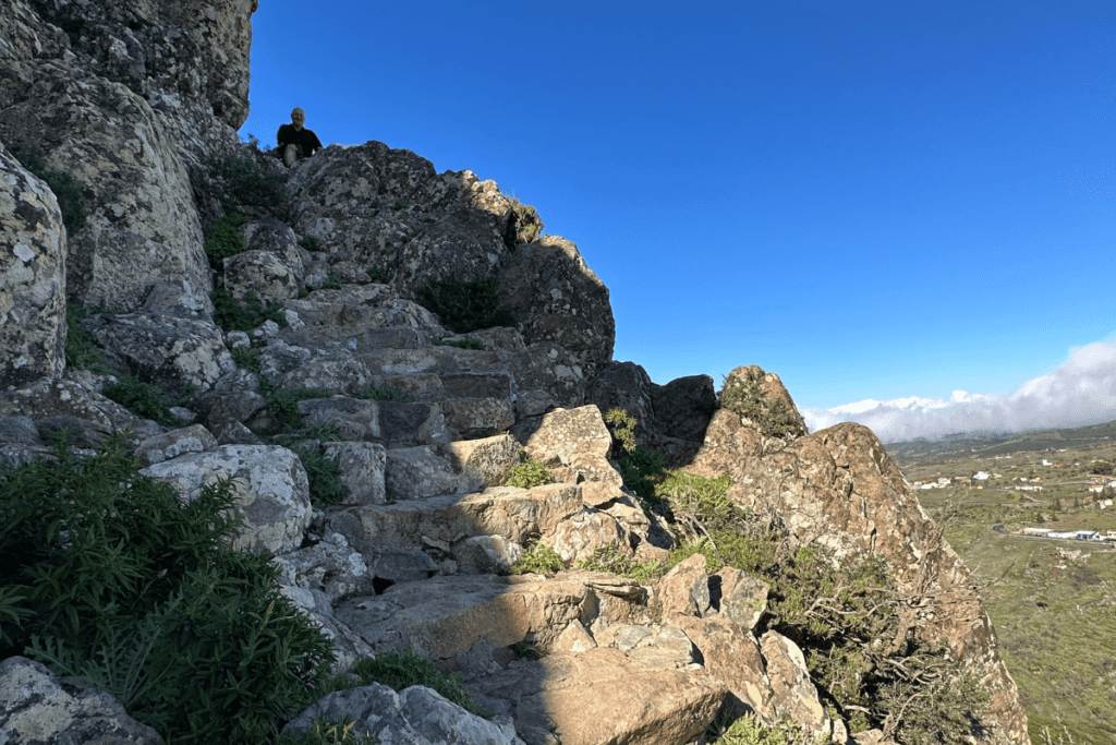 Ripidi gradini in pietra con uomo seduto vicino alla cima La Gomera escursionismo a La Fortaleza De Chipude Isole Canarie Spagna