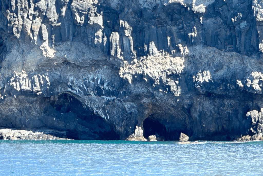Blaues Meer vor Höhlen in der Nähe von Playa De Iguala La Gomera Kanarische Inseln Spanien mit steilen Bergen im Hintergrund