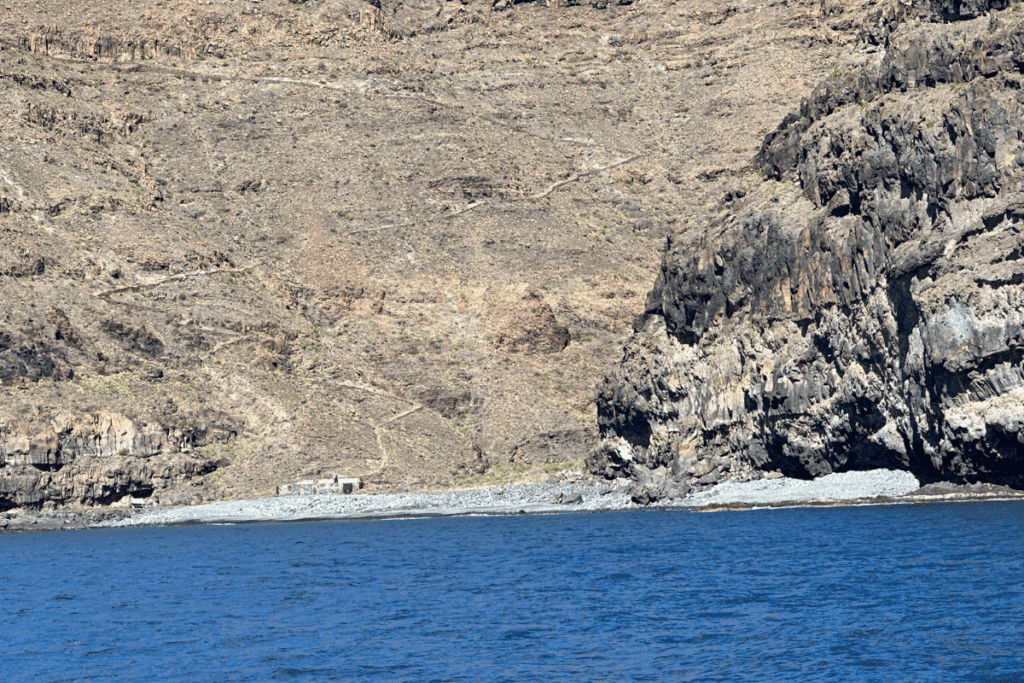 Una pista empinada recorre la montaña hasta Playa de Iguala La Gomera Islas Canarias España con mar azul en primer plano