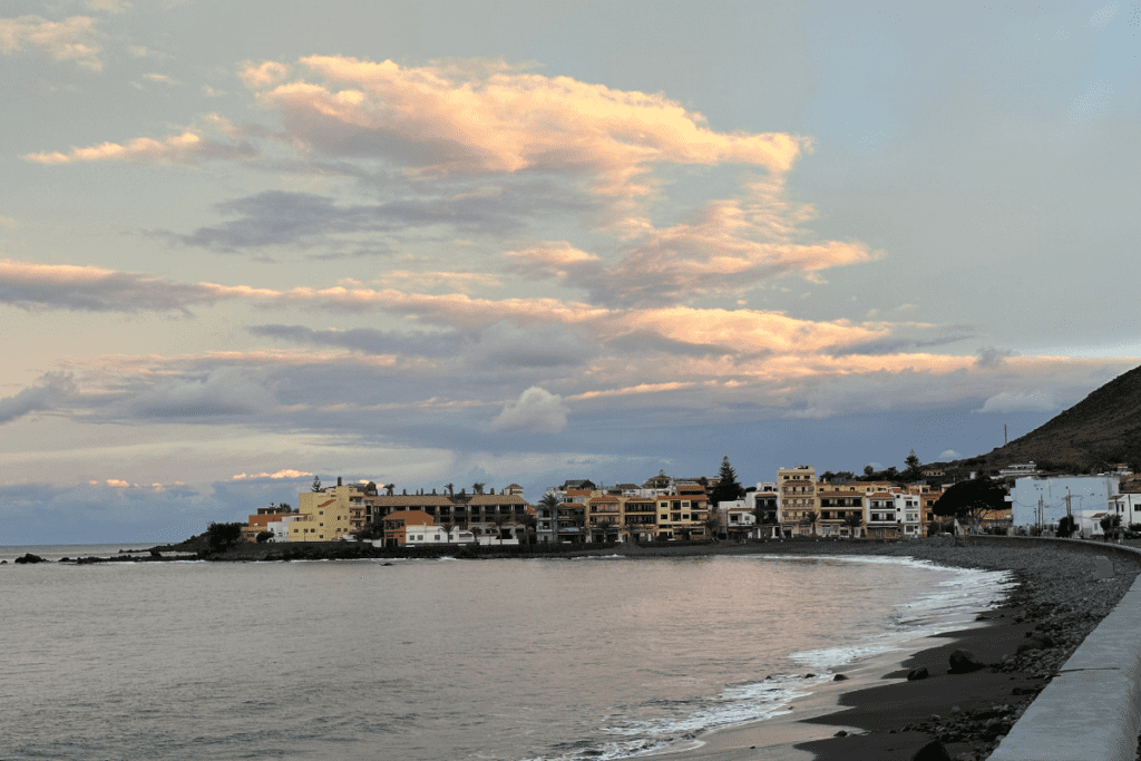 Una spiaggia di sabbia e ciottoli all'alba chiamata Playa De La Calera La Gomera Isole Canarie Spagna con ristoranti e alberghi in background