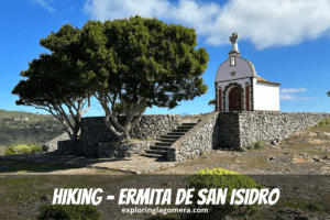 La bella Ermita De San Isidro La Gomera Isole Canarie Spagna si trova sopra il muro di pietra con albero in primo piano e cielo blu e nuvola bianca