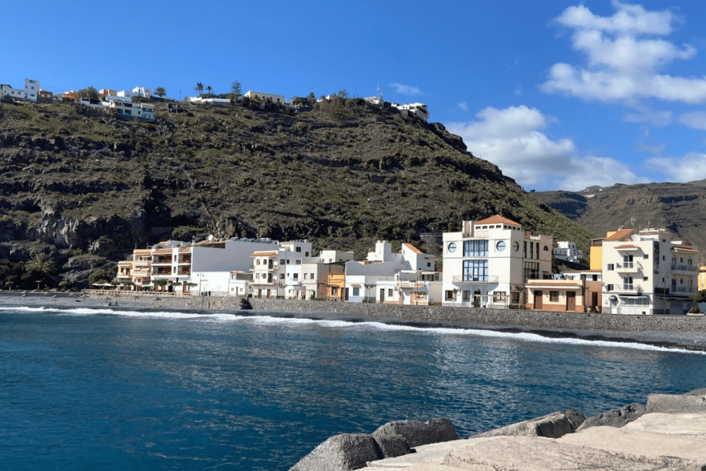 Ein Blick auf die Promenade mit Cafés und Restaurants an der Playa De Santiago La Gomera Kanarische Inseln Spanien, aufgenommen vom Pier mit blauem Meer im Vordergrund