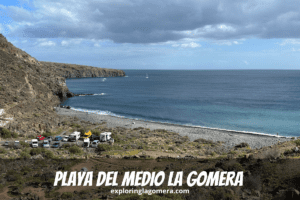 Der Fußweg nach Playa Del Medio, La Gomera, Kanarische Inseln, Spanien, aufgenommen an einem sonnigen Tag mit blauem Himmel und blauem Meer, zeigt auch Autos auf einem kleinen Parkplatz