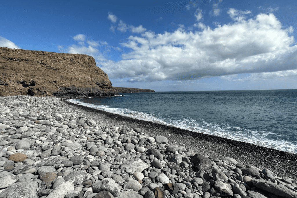Una costa rocciosa di origine vulcanica con il blu del mare e del cielo a Playa de Tapahuga, una delle migliori spiagge di La Gomera, Isole Canarie, Spagna